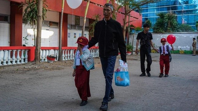 Dua orang tua menggandeng anaknya menuju ruang kelas pada hari pertama tahun ajaran baru di SD Negeri Sudirman, Makassar, Sulawesi Selatan, Senin (13/7/2026). (ANTARA FOTO/HASRUL SAID)