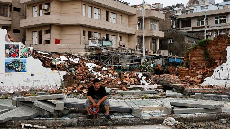 Foto: Seseorang duduk di samping tembok yang runtuh pasca Topan Bavi di desa pesisir Dongsha, Taizhou, provinsi Zhejiang, China, 12 Juli 2026. (REUTERS/Go Nakamura)